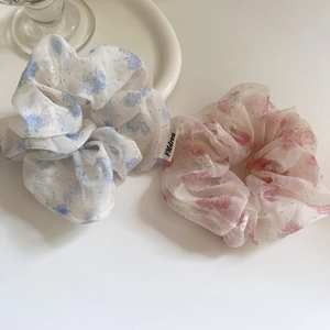 Vue détaillée de deux chouchous en organza à fleurs bleu et rose sur une surface blanche