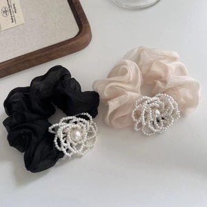 Dettaglio di eleganti elastici in tulle nero e champagne con fiori di perle