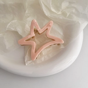 Detail of light pink acetate star hair claw clip with golden metal spring mechanism