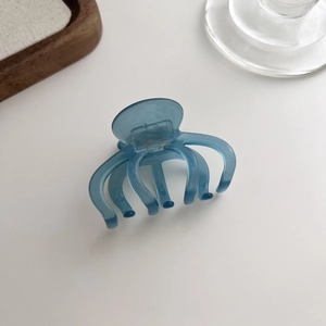 Detail of blue acetate hair claw clip showing France Handmade engraving on white surface