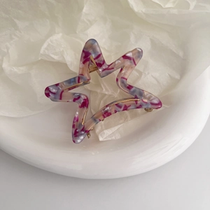 Close-up of a hollow star hair claw with purple marble pattern on a white tray