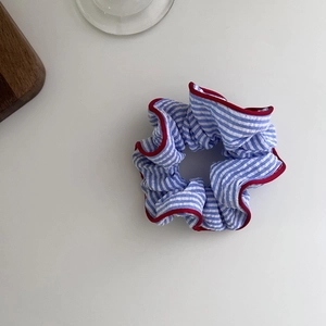 Detail of blue striped scrunchie with red piping and elegant fabric pleats