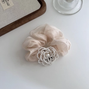 Dettaglio di elegante elastico in organza con fiore di perle e tessuto color oro champagne