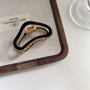 Detail showing high-quality black acetate shell and golden metal spring of the hair claw