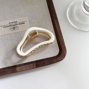 French style cloud acetate hair claw clip with golden metal inner on a wooden tray