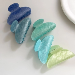 Dettaglio di cinque mollette per capelli in acetato marmorizzato in tonalità blu e verdi
