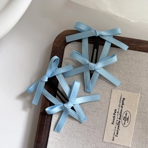 Drei hellblaue Haarklammern mit Schleife aus Satin auf einem Holztablett Detail