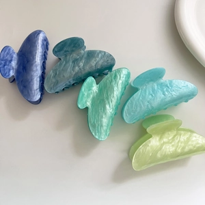 Dettaglio di cinque mollette per capelli in acetato marmorizzato nei toni verde e blu