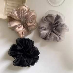 Detailed view of champagne, grey, and black double-layer mesh scrunchies on white background
