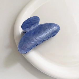 Molla per capelli con trama marmo blu in acetato su un vassoio bianco minimalista