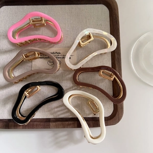 Detailed view of six colors of cloud acetate hair claws with gold metal springs on a board