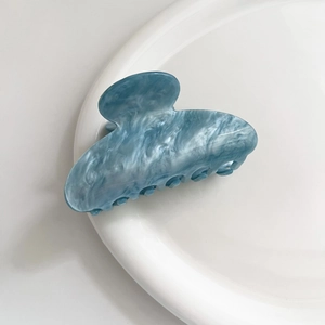 Dettaglio del fermaglio per capelli in acetato azzurro con texture marmorizzata