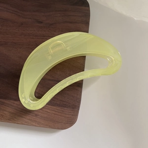 Macro detail of translucent lime green resin hair claw clip with sturdy metal spring