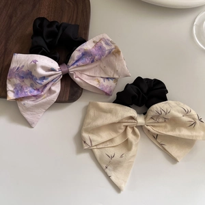 Detail view of floral and leaf pattern bow hair scrunchies with elegant linen texture