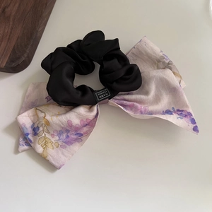 Close-up of handmade floral bow scrunchie with satin texture and detailed floral pattern