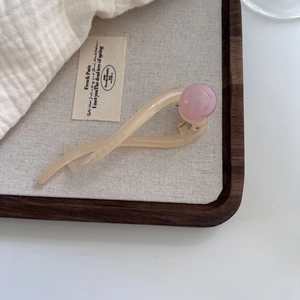 Macro detail of cream-colored acetate twist hair clip with pink marble bead accent