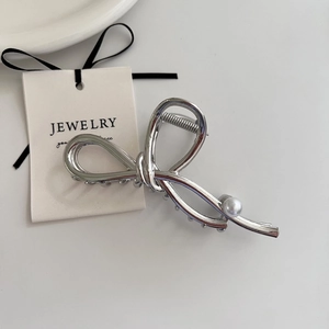 Close-up of silver metal bow hair claw with pearl detail and elegant spiral spring