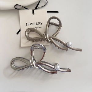 Detailed view of silver bow hair claw clip with pearl accents and metal spring mechanism