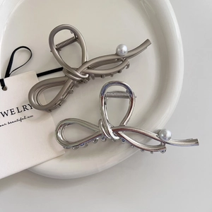Detail of elegant silver and champagne metal hair claws with pearl bow design