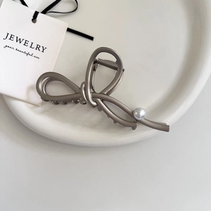 Elegant matte silver metal hair claw clip with flowing bow design and pearl accent
