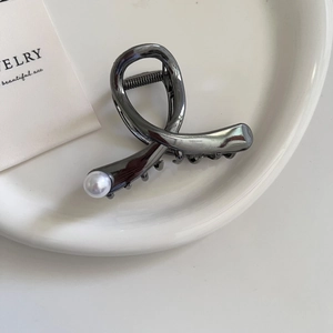 Close-up of gunmetal grey hair claw clip with crossing metal lines and white pearl accent