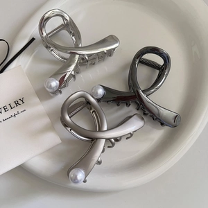 Three metallic pearl hair claws in silver, black, and champagne colors on a white plate