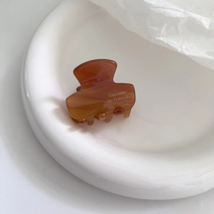 Close-up of amber brown acetate hair claw with Barrette la France script on ceramic tray