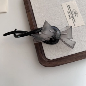 Détail d'une barrette nœud gris translucide avec coutures ajourées sur pince banane