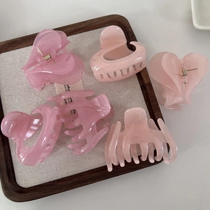 Detailed view of jelly pink resin hair claws in heart and classic shapes on a tray