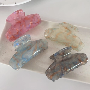 Détail de quatre pinces à cheveux en acétate aux textures marbrées et tons pastels