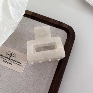 Detail of a cream marble acetate hair claw clip with a hollow rectangular geometric design
