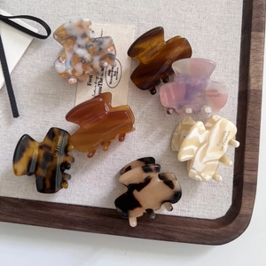 Detail view of 7-piece marble pattern acetate hair clips in a textured display tray