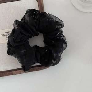 Detail of black lace hair scrunchie with delicate white pearls and French embroidery texture