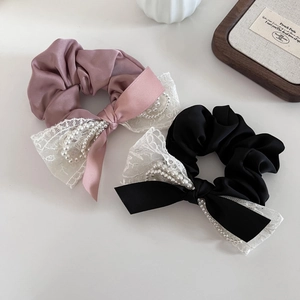 Détail de chouchous à nœuds en dentelle et perles en tissu satiné rose et noir