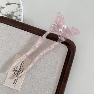Detail of pink butterfly hair pin with marble texture and pearls in a wooden box