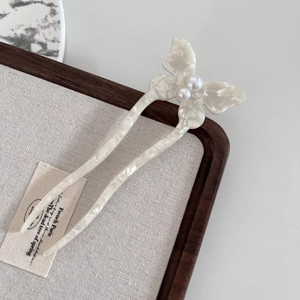 Detail of elegant butterfly hair fork with white marble texture and pearl accents