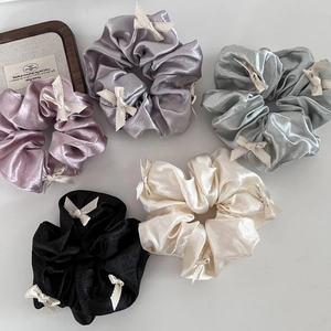 Flat lay of satin scrunchies with lace bows in pink, purple, silver, black, and cream colors