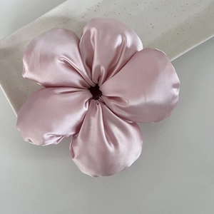 Chouchou fleur en satin rose sur un plateau en céramique pour une coiffure élégante