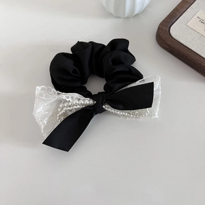 Vue détaillée d'un chouchou en dentelle avec perles d'imitation sur tissu satiné