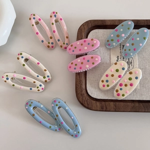 Detailed view of colorful polka dot oval hair clips in various pastel macaron colors