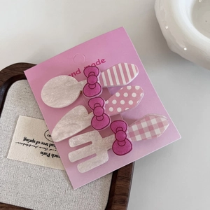 Close-up of pink bow hair clips set with cute cutlery shapes on handmade card paper