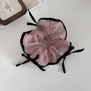 Chouchou en organza rose avec bordure noire et nœuds sur un fond neutre épuré