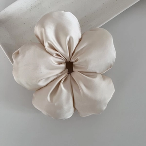 Détail d'un grand chouchou fleur en satin champagne avec des pétales rembourrés