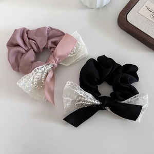 Détail de chouchous en dentelle satinée avec perles fantaisie en rose et noir