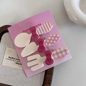Detail of pink bow cutlery hair clips set featuring spoons and forks on a card