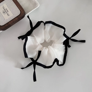 Chouchou élégant en tulle blanc avec bordure noire et petits nœuds sur fond clair