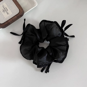 Chouchou élégant en tulle noir avec de délicats nœuds sur un fond gris minimaliste