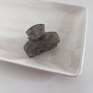 Starry dark grey acetate hair claw with marble texture and gold glitter in ceramic tray