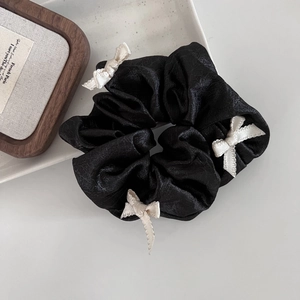 Elegant ballet style black satin scrunchie with cream white bows on ceramic tray