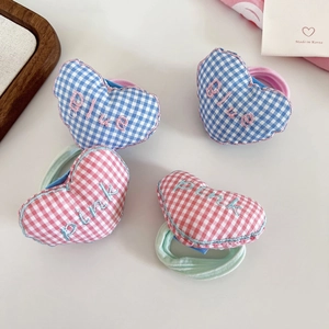 Close-up of embroidered heart-shaped hair ties with blue and pink plaid fabric patterns
